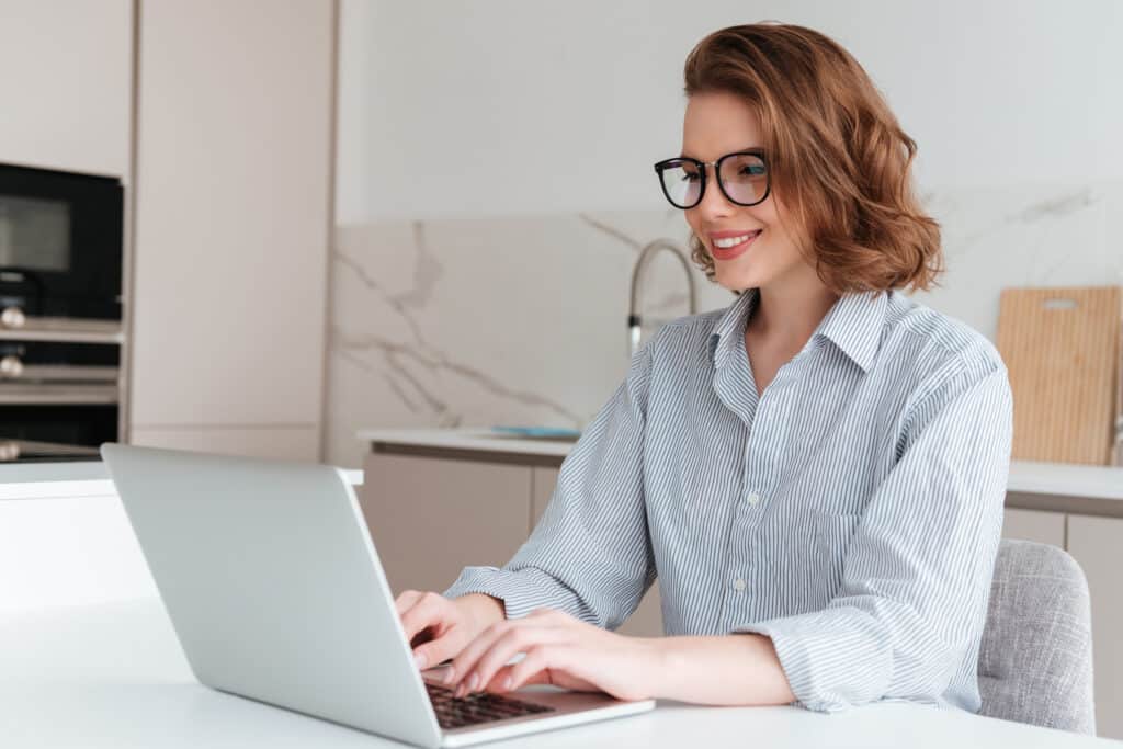 Elegant smiling woman in glasses and striped shirt using laptop